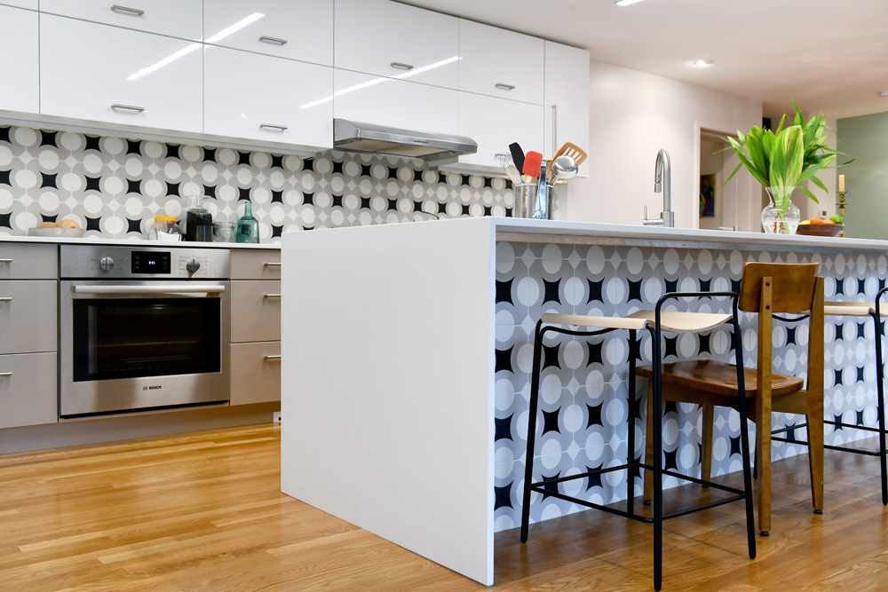 A sleek white kitchen with patterned backsplash and island