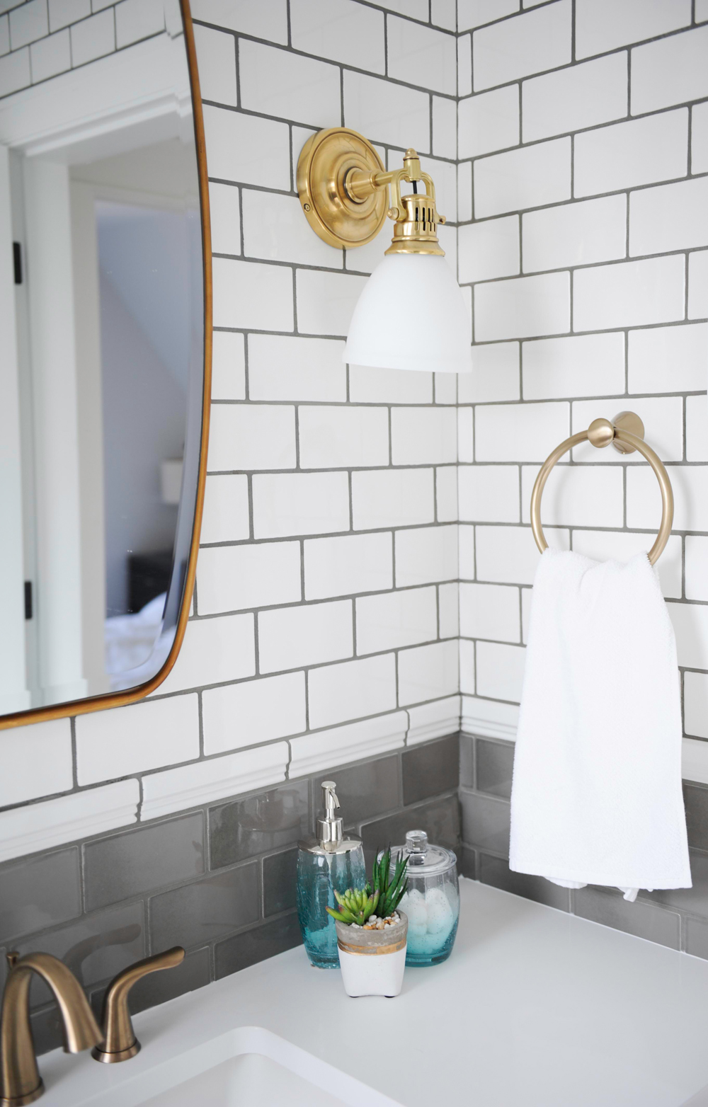 brass and copper bath sconces, handtowel holder and mirror fixtures and grey and white subway tiles