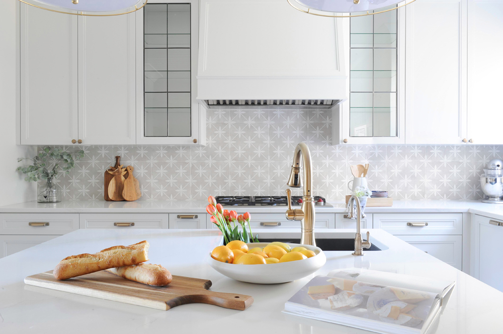 kitchen island with baguette, cutting board, bowl of lemons and view to patterned backsplash