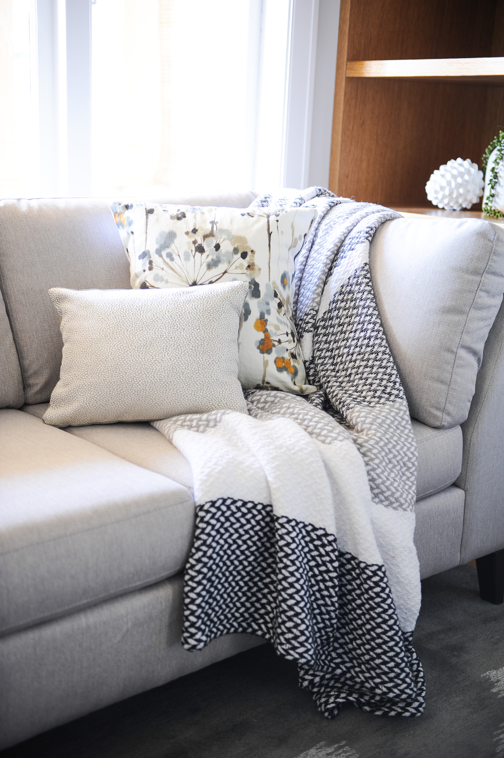 two cushions and grey white and black throw on a grey sofa