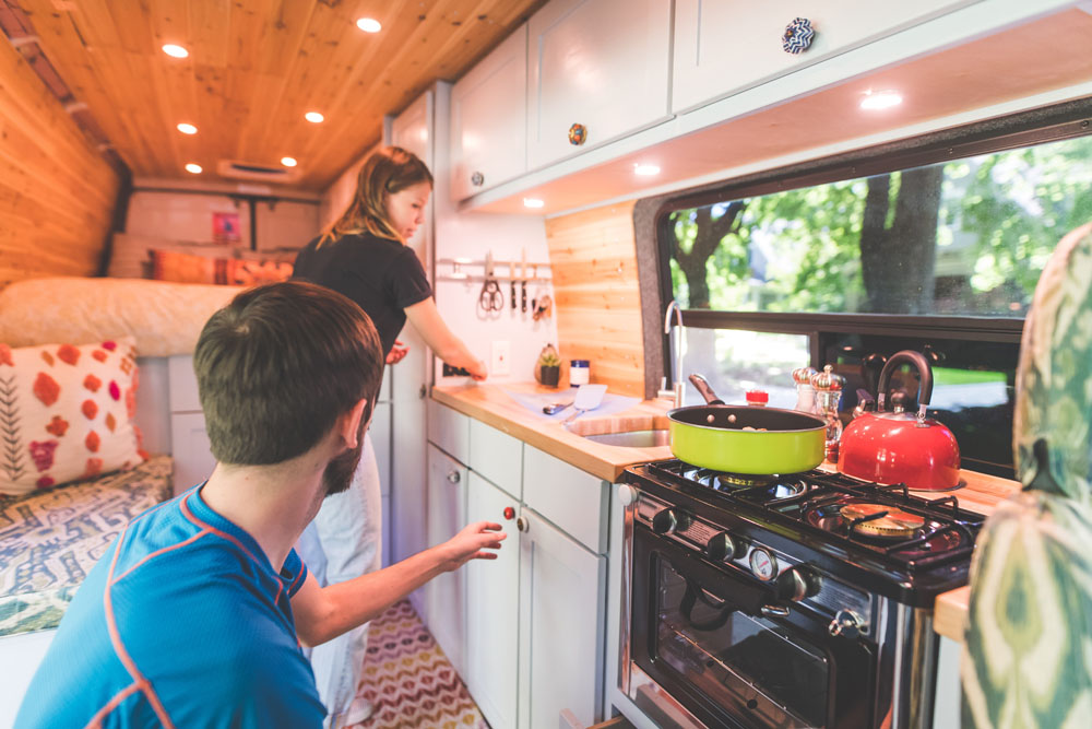 Millennial couple cook breakfast in the van they live in