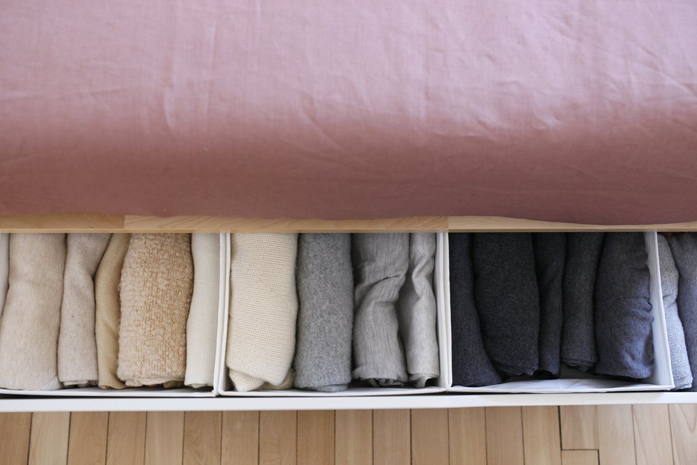 folded blankets in pullouts under bed with pink sheet