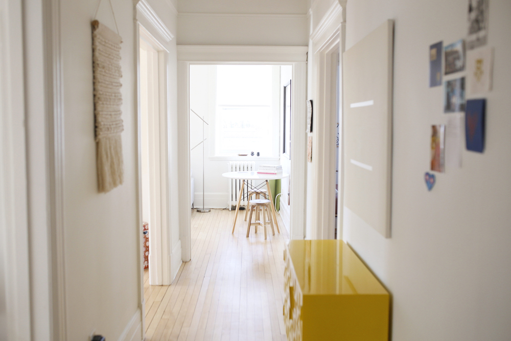 white hallway with yellow glossy dresser on right