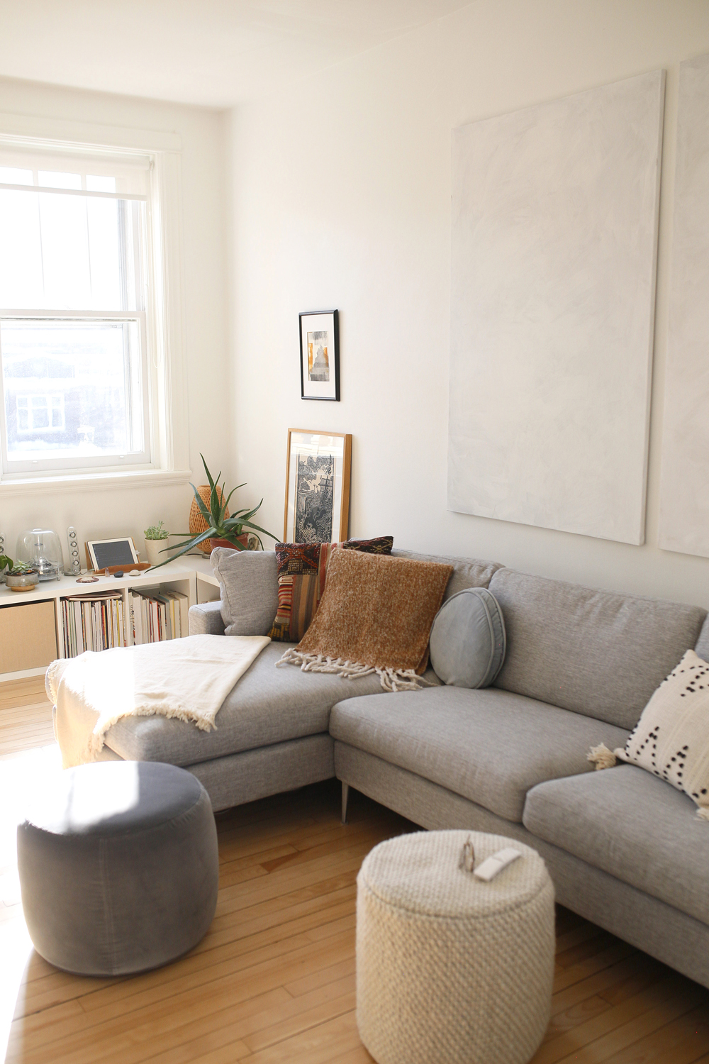 grey sectional, two soft ottomans, sunlight