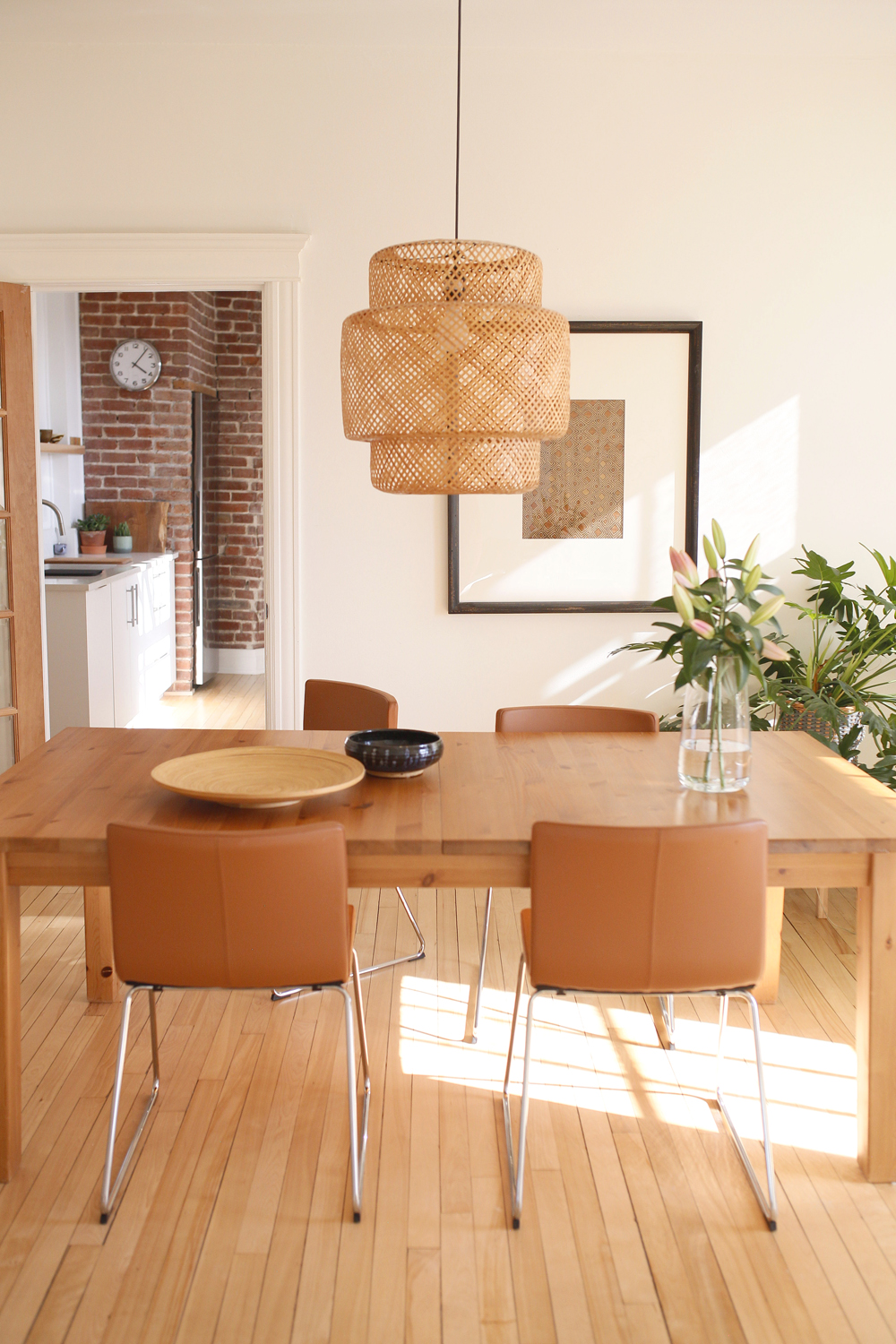 wicker pendant light, four caramel dining chairs, table, sunlight