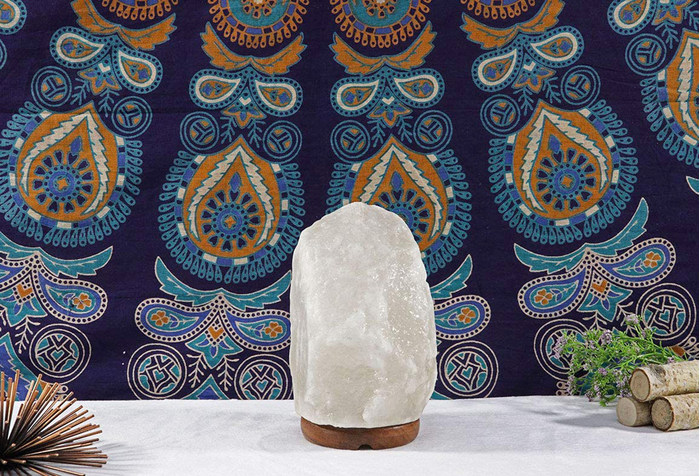 A Himalayan salt rock lamp on a table against a patterned blue background