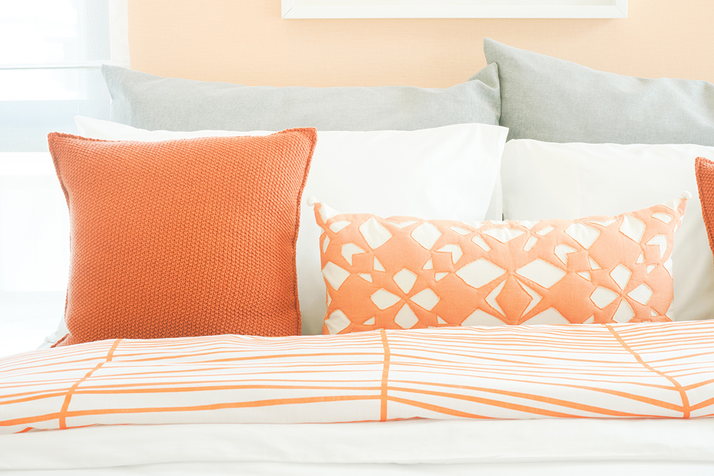 Closeup pillows on bed, orange and gray color scheme