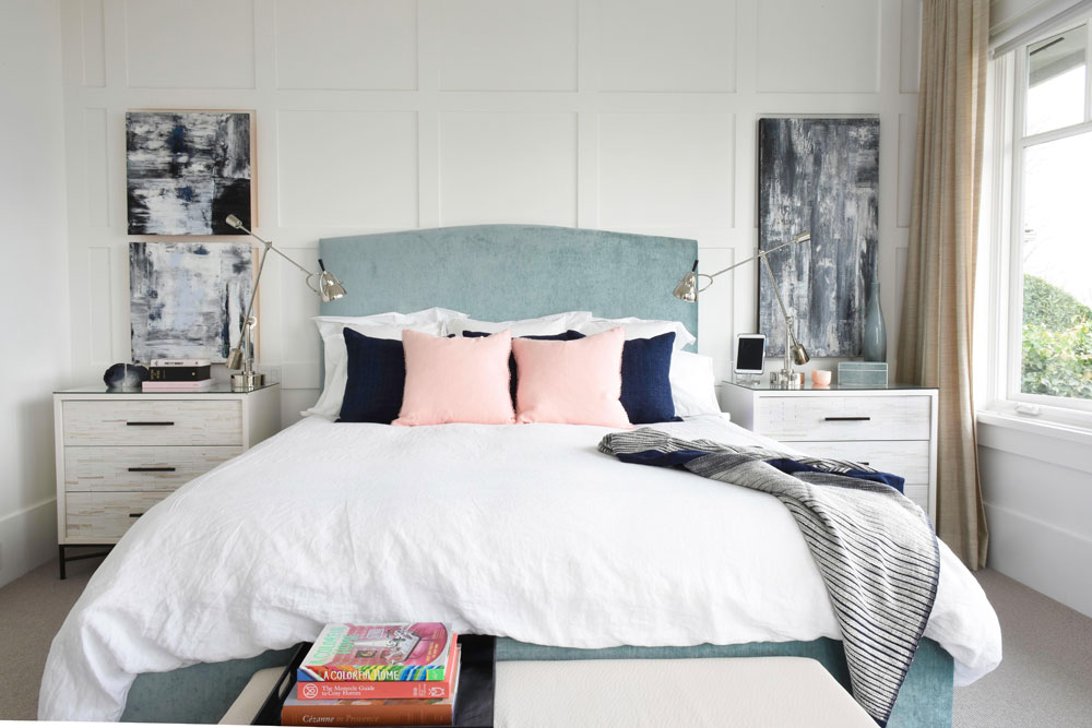 White bedroom with a pale blue frame, white duvet cover, pink and navy blue pillows