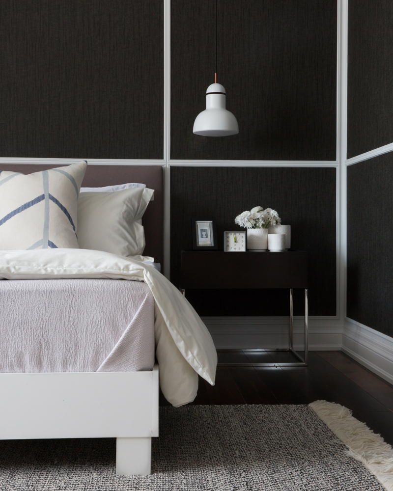 Bedroom with dark wood walls, white bed frame and dark wood and metal night side table