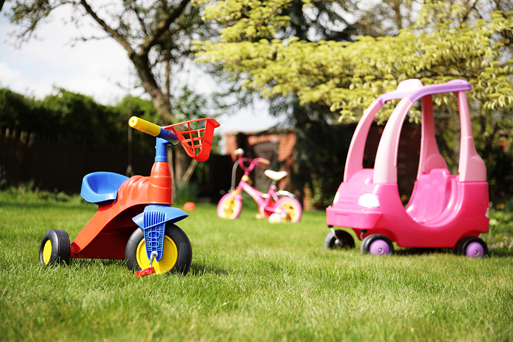 A yard with three children's toys in it