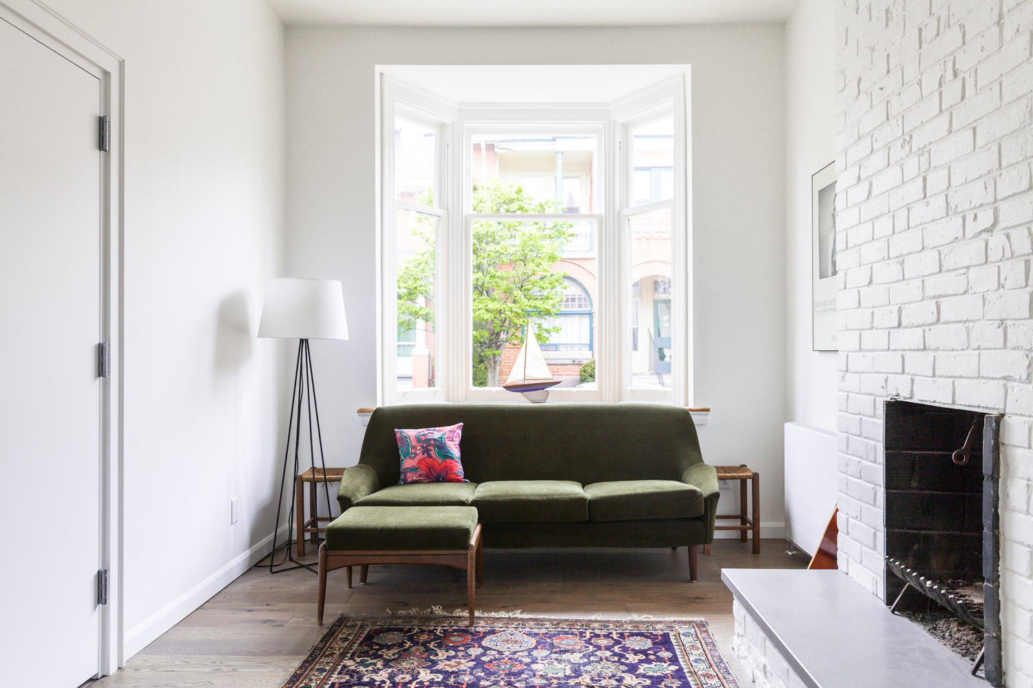 Green sofa against a bay window in a small white living room