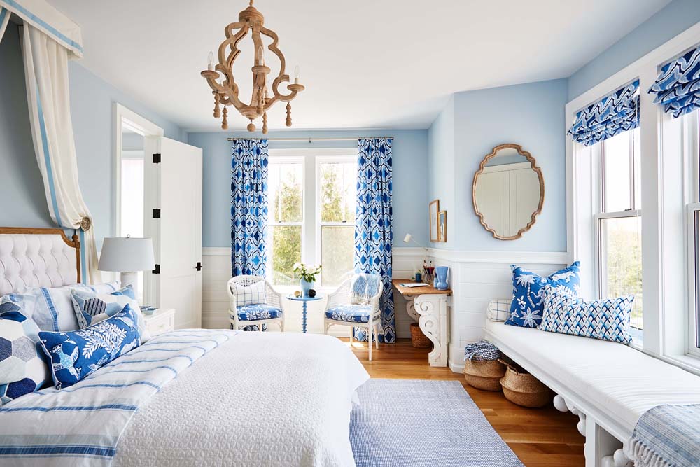 Vibrant blue and white bedroom with tons of natural light and a bronze chandelier