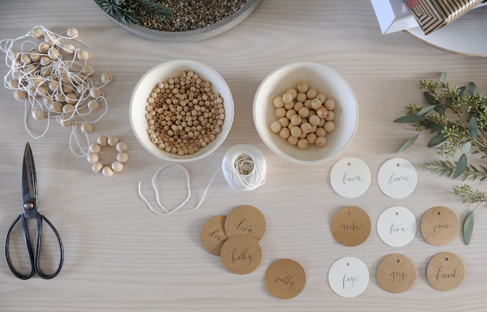 two bowls of wooden beads, name tags, string and scissors