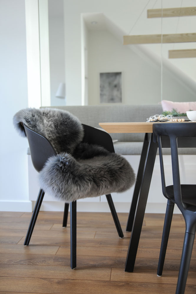 shot of black chair with grey fur throw on it, wood floor