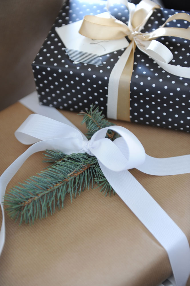 kraft paper wrapped git with pine bough, white ribbon and other gift box on it