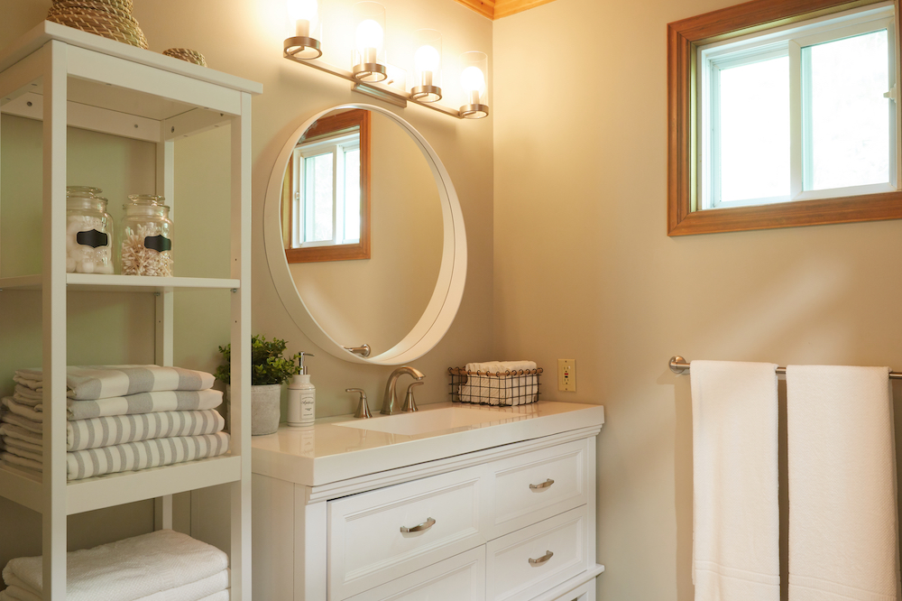 contemporary rustic bathroom with white vanity and round mirror