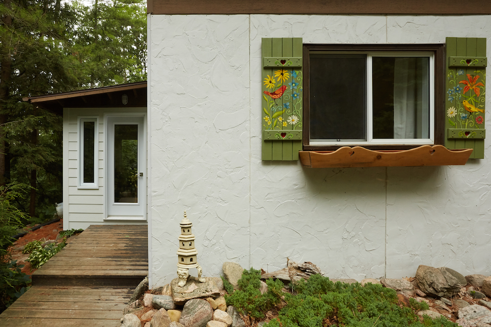 white cottage exterior with colourful folk-art-painted window shutters