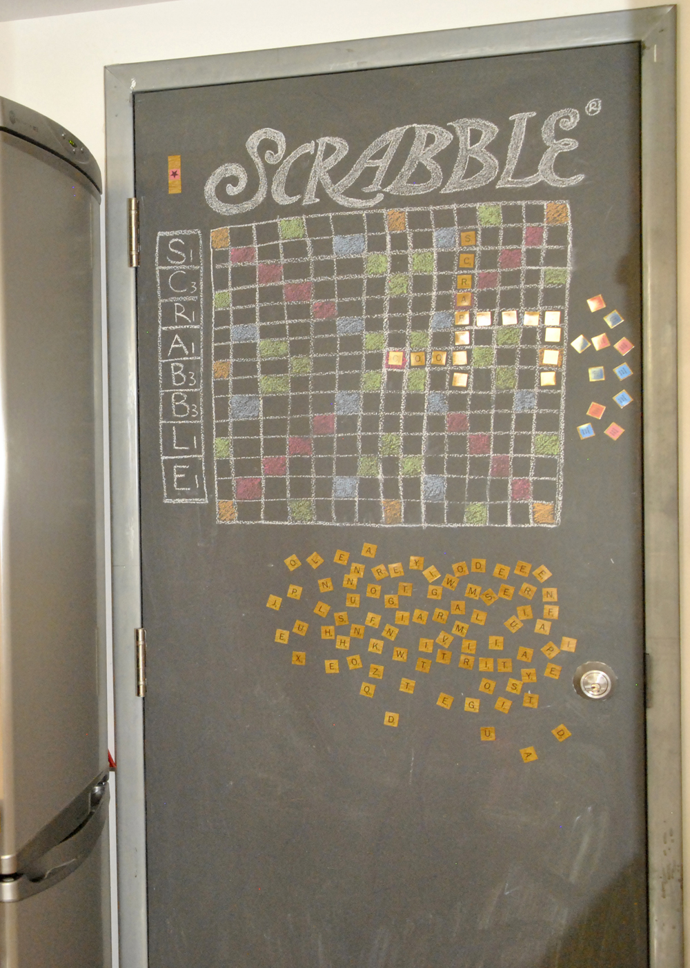A door in basement kitchen that is painted with chalkboard paint and contains an illustrated Scrabble board