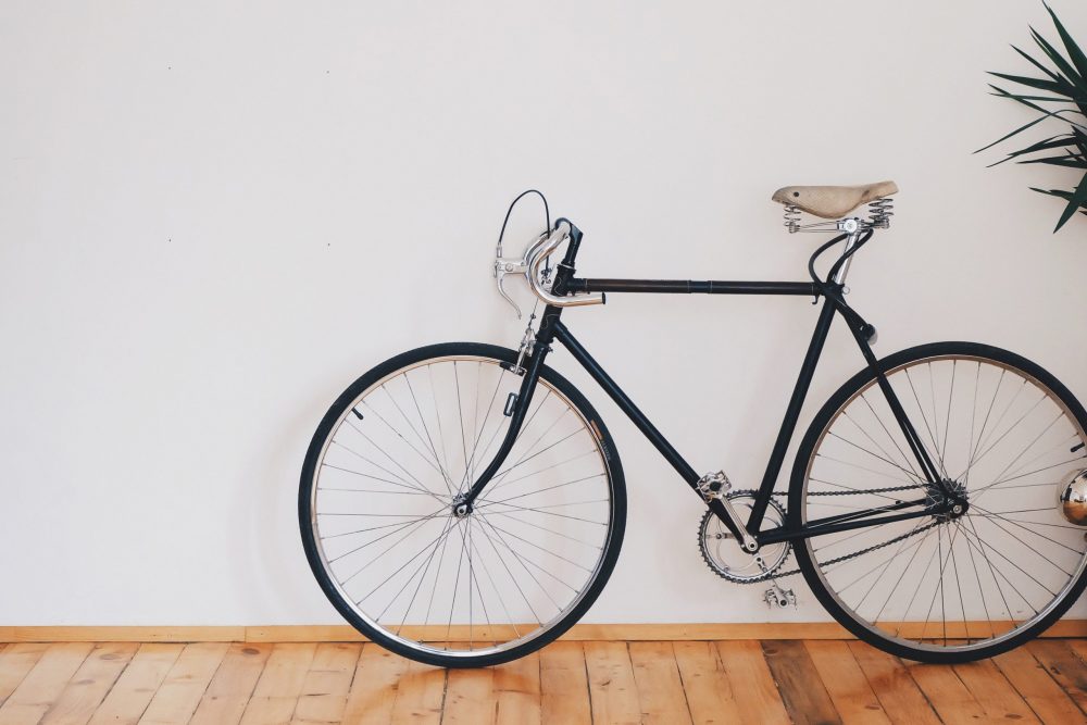 A black bicycle leaning against a white wall inside a house or apartment