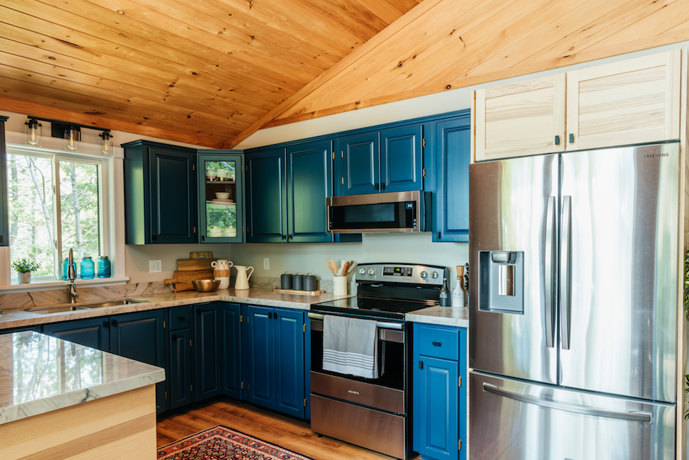 A renovated kitchen with blue cabinetry and a rustic wood ceiling