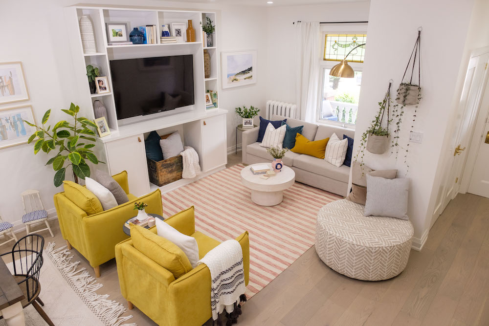 A renovated living room with a large TV, plenty of seating and a striped area rug