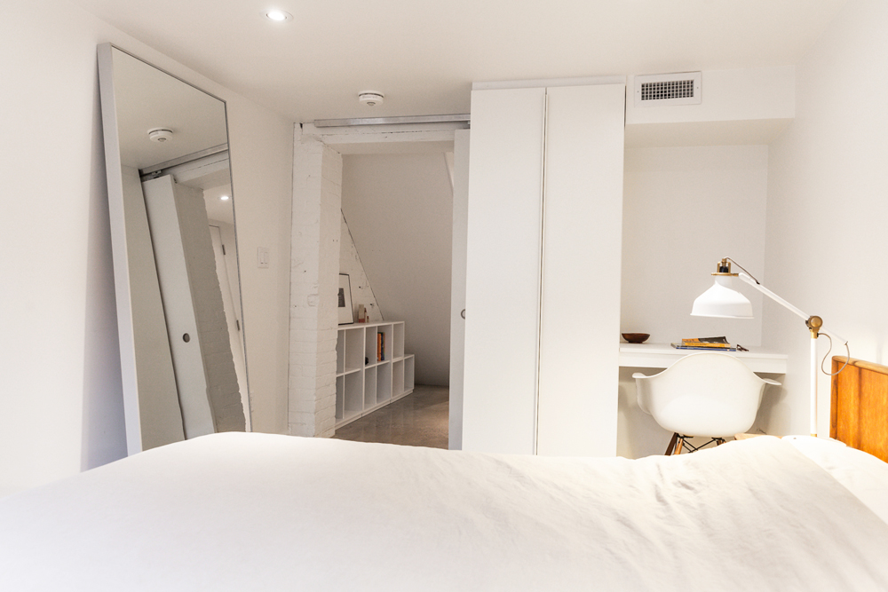 A basement bedroom with a subtle white doorway that leads into a separate room