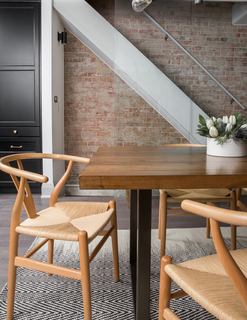 A stylish kitchen with exposed brick and a hidden staircase that leads down into the basement