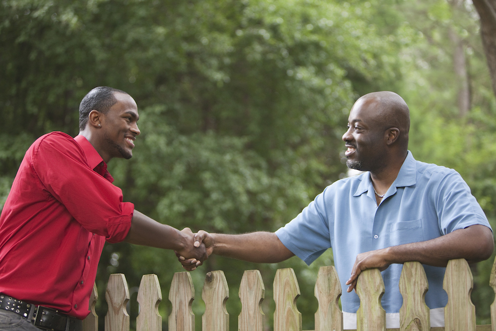 neighbors greeting each other over fence
