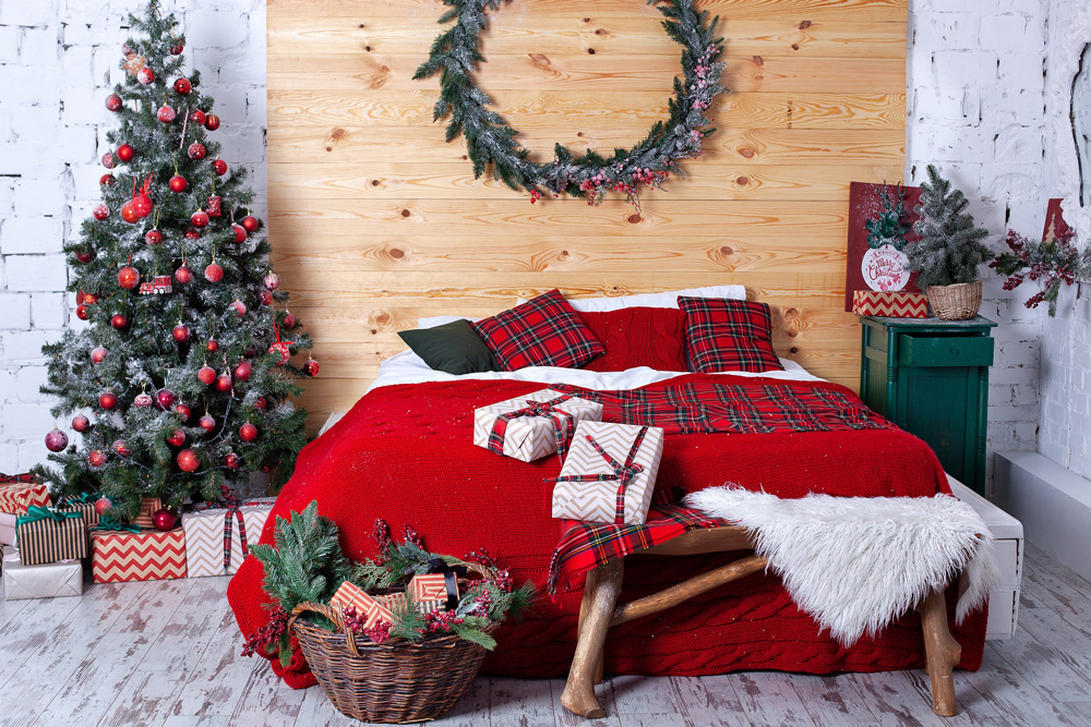 New Year decorated bedroom. Spacious rustic white bedroom with decorated Christmas tree and Christmas wreath on wall. Xmas in morning bedroom. Double bed In christmas Interior on wood wall background