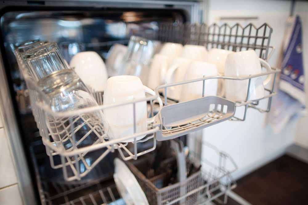 A picture of a dishwasher, door ajar, filled with clean dishes.