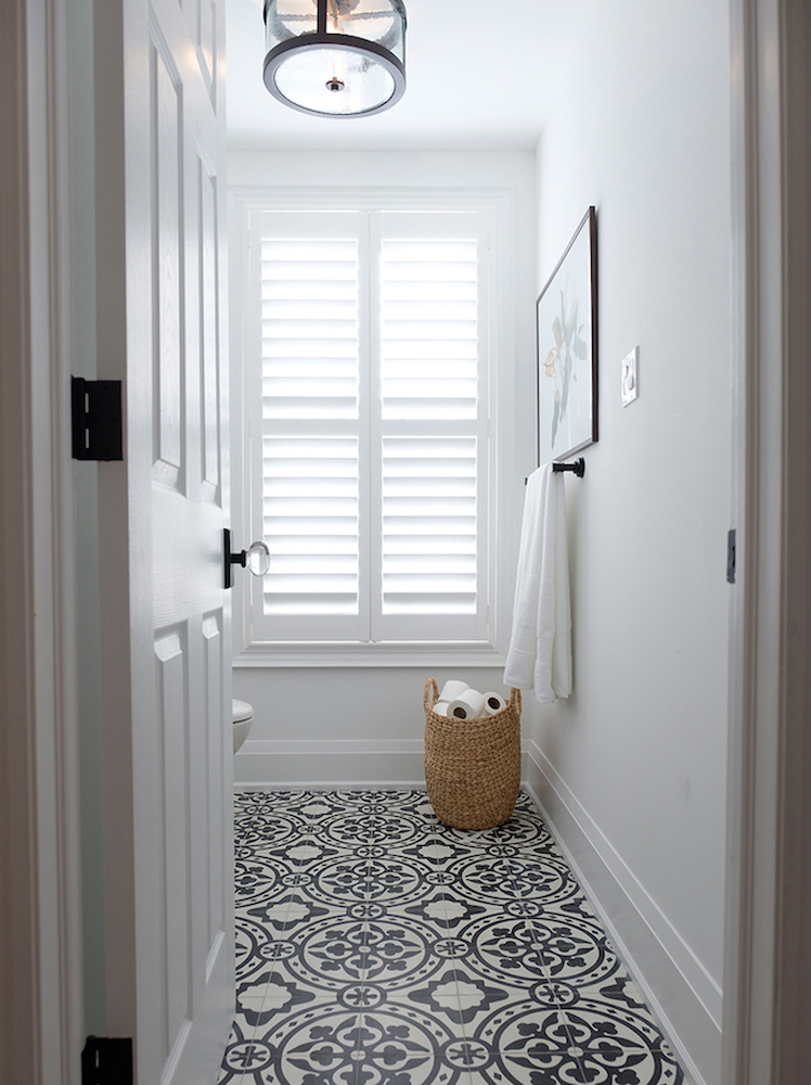white bathroom with black-and-white floor tiles and basket on floor