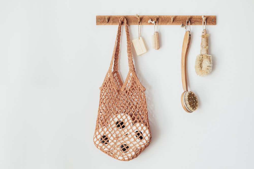 wooden hooks with bag and loofahs on white wall