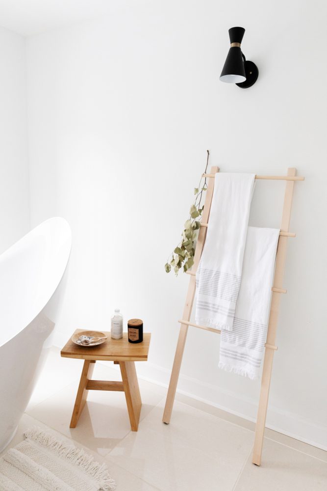 minimal white bathroom with wood towel ladder and small wood stool