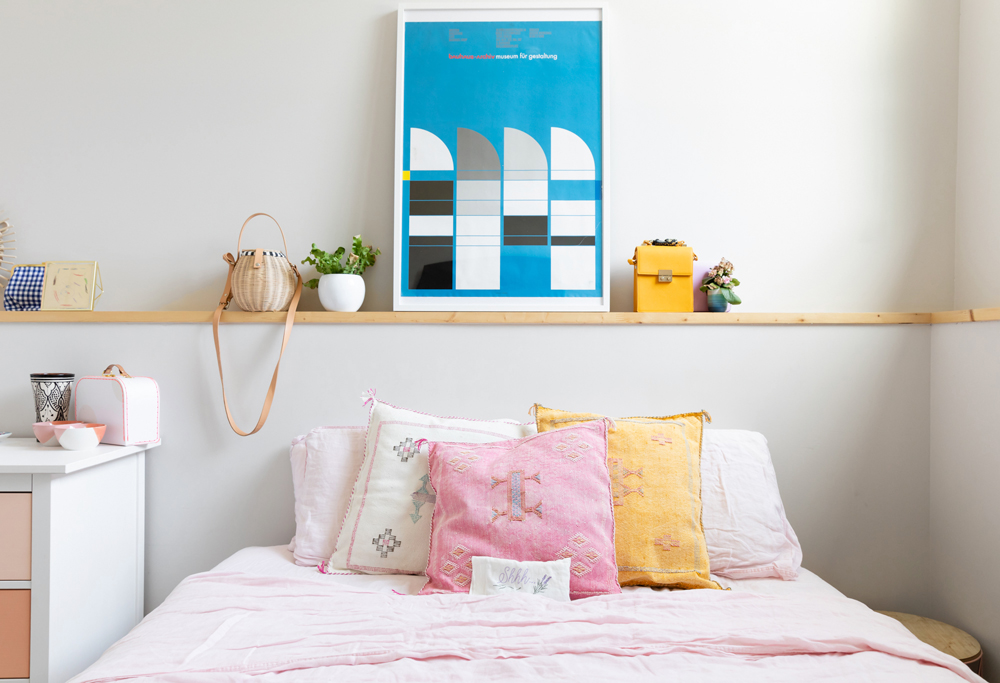 bright, colourful bed with wooden ledge shelf with assorted decorative items
