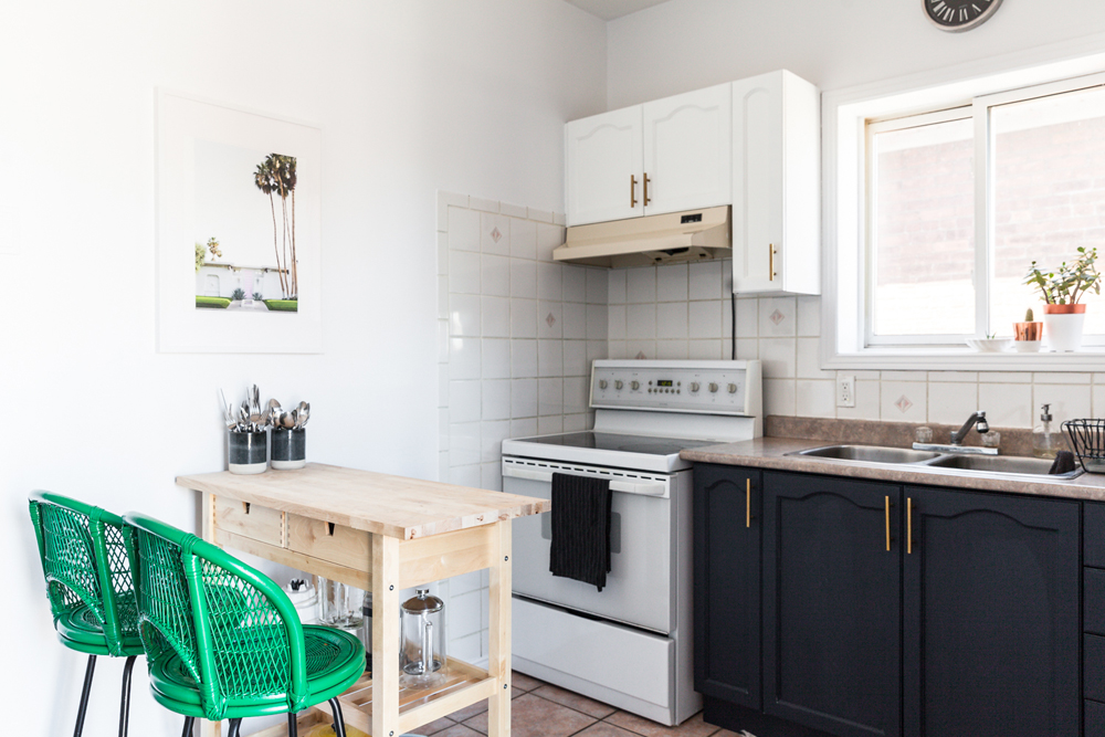 A tiny wooden table with bright green chairs in a tiny kitchen space