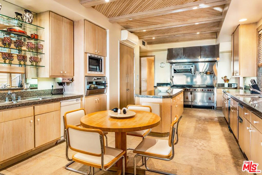 A modest eat-in kitchen with a gigantic, commercial-grade range over the stove and high ceilings