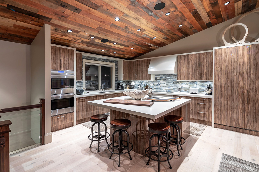 A large rustic kitchen with sloped wood ceilings and bar-style seating at the island