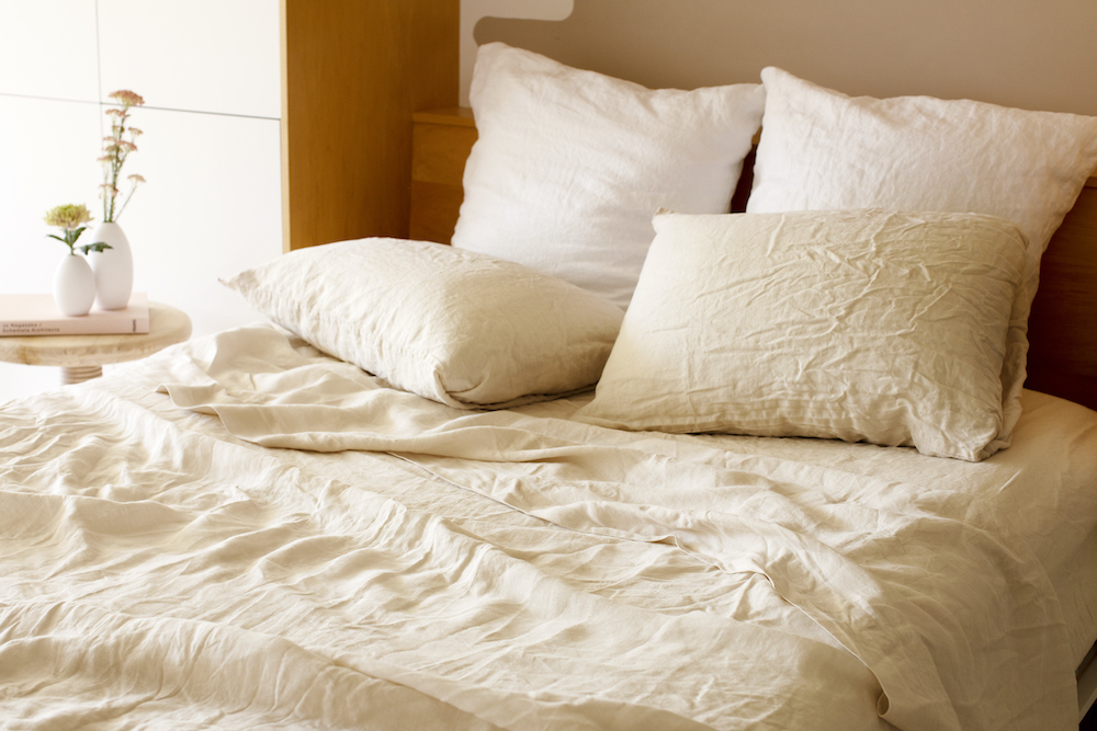 cozy beige bed with linen sheets and pillows on top