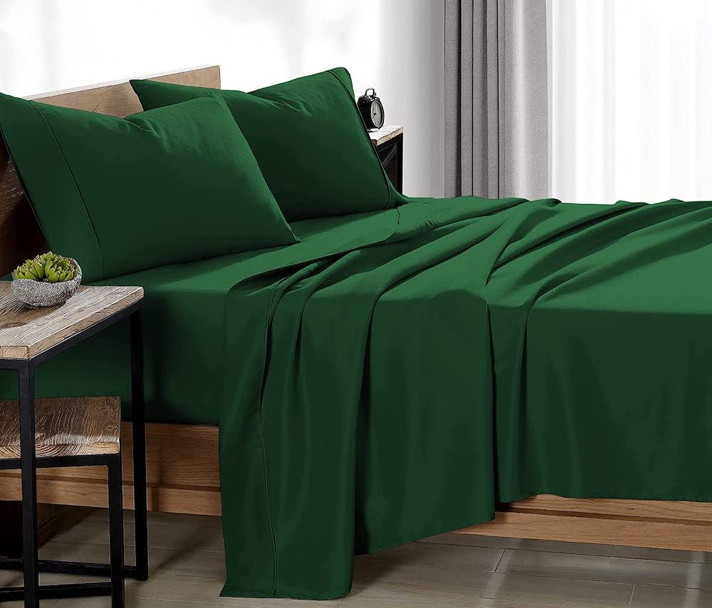 wooden bed with green sheets and pillows