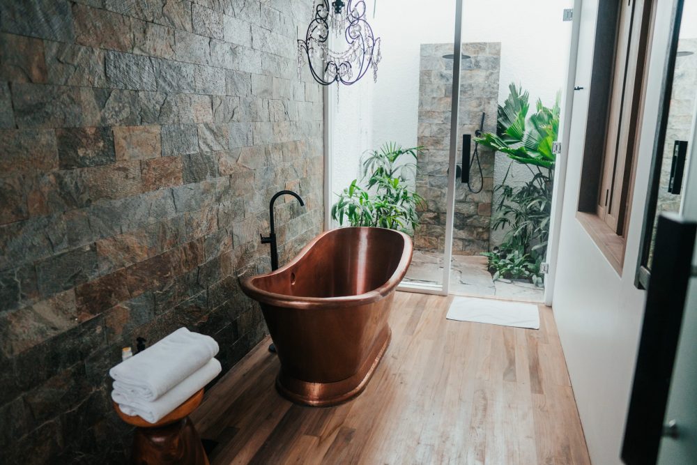 bathroom with brick walls, cooper bathtub and shower with plants