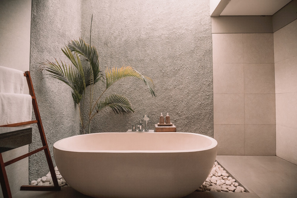 zen minimal bathroom with oval white bathtub and large green plant