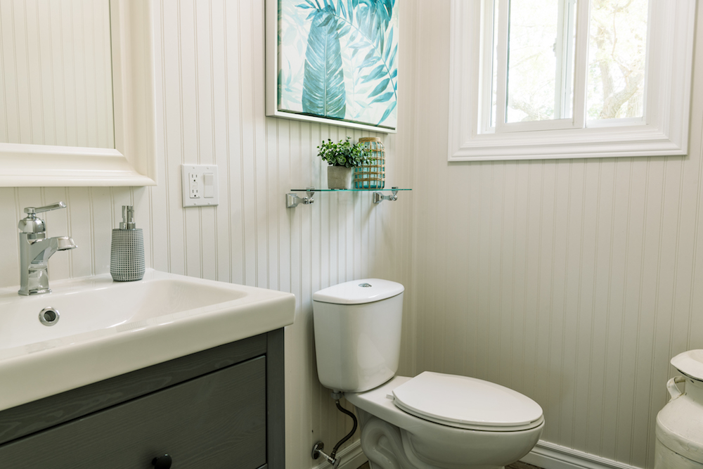 white powder room with textured white walls and blue wall art