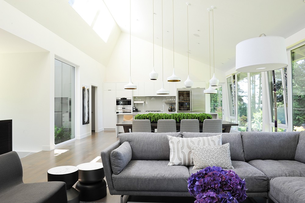 Living room with hanging light fixtures, plenty of seating space and an attached kitchen