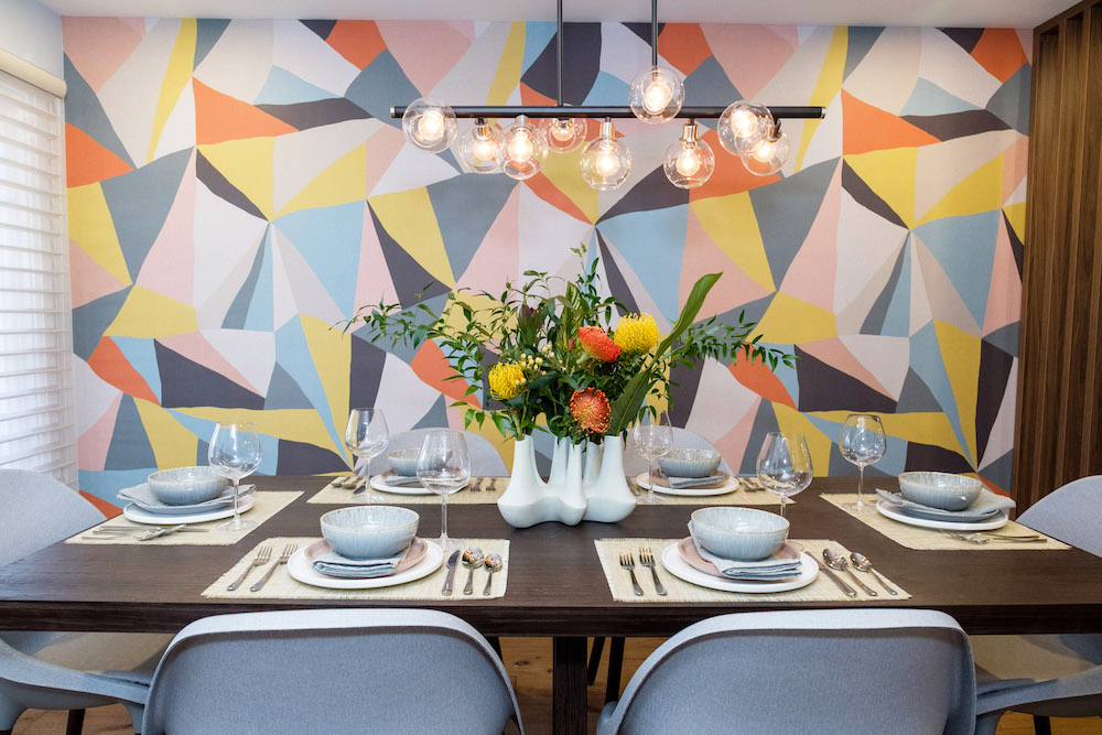 Multi-coloured abstract accent wall in a small dining room with seating for six