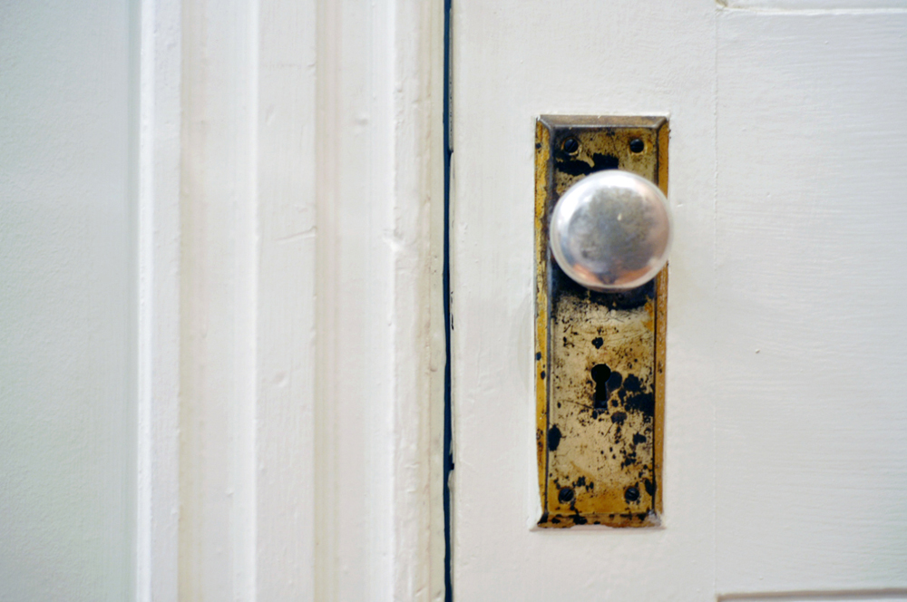 A closeup of a doorknob on a white door