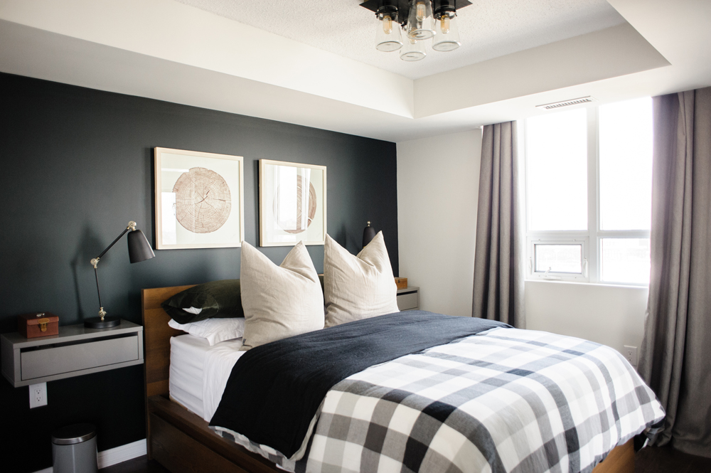 Master bedroom with black accent wall and queen-sized bed with checkered comforter