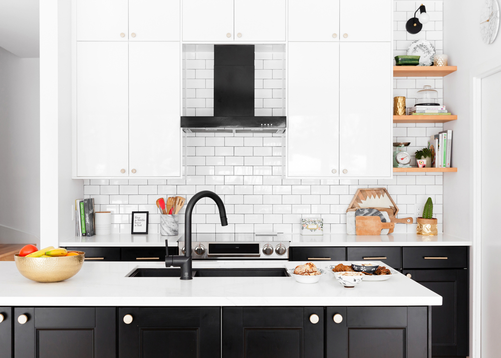 A classic black-and-white kitchen with an island featuring a double sink in black matte