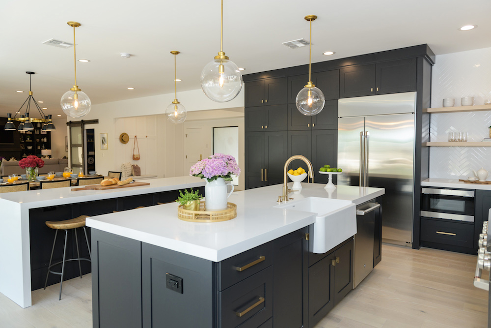 A black and white farmhouse-style kitchen with two dueling kitchen islands and large bubble light fixtures