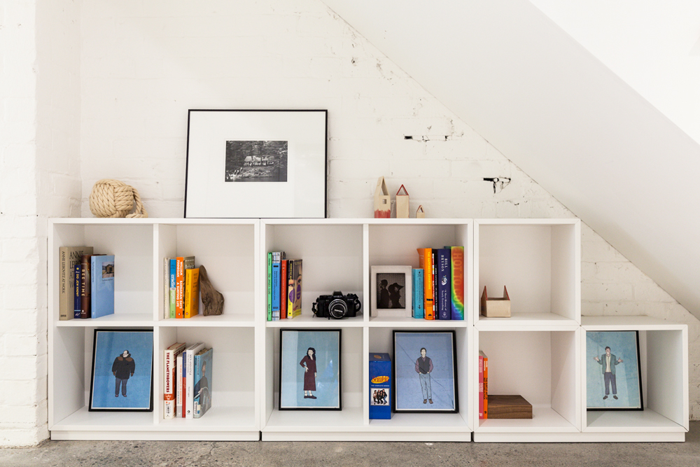 A well-organized open shelving area with books and picture frames in the nook under the stairs