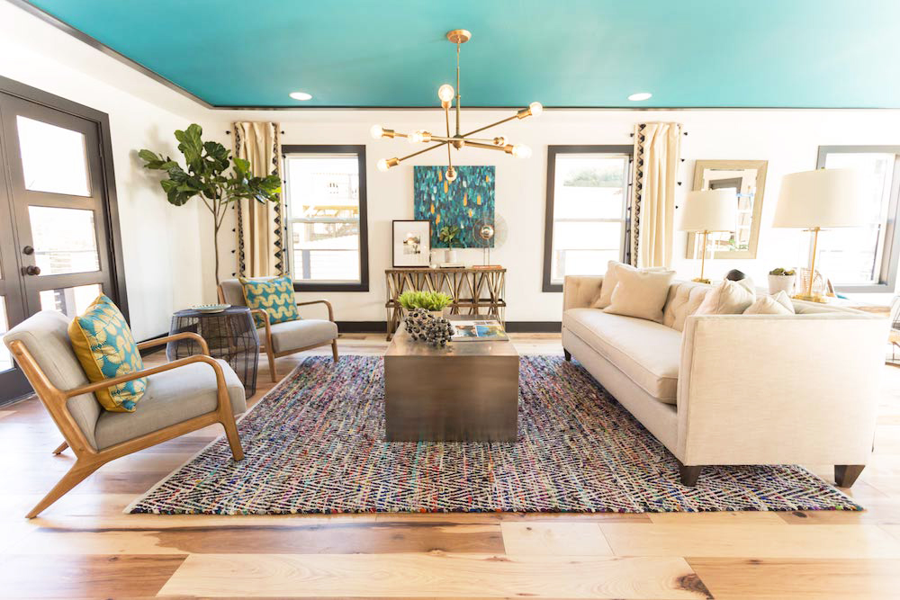 A living room with neutral furniture and a teal accent ceiling that adds a punch of colour